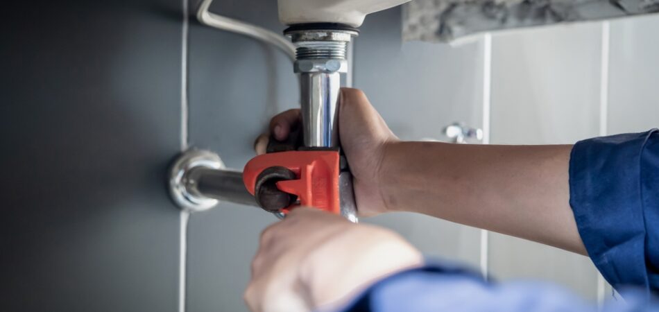 Plumber,uses,wrench,to,repair,water,pipe,under,sink,there