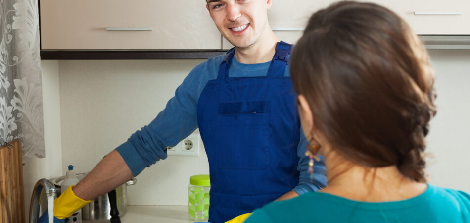Smiling,plumber,repairing,a,running,water,for,woman