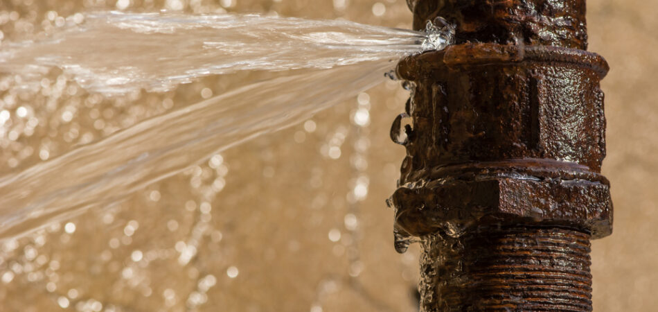 Rusty,burst,pipe,spraying,water,after,freezing,in,winter.